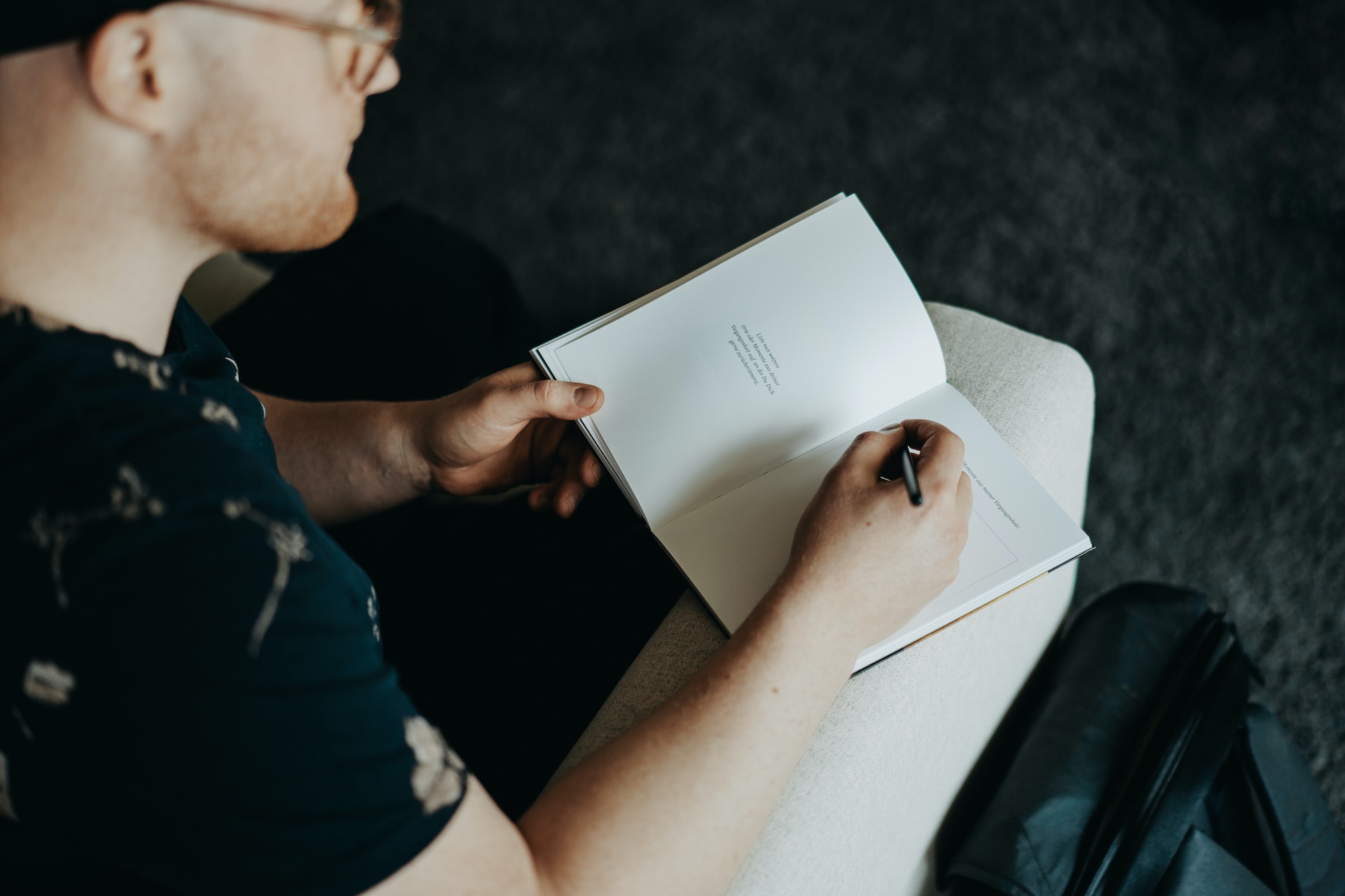 seated young man with glasses using healthy coping skills writing in a notebook