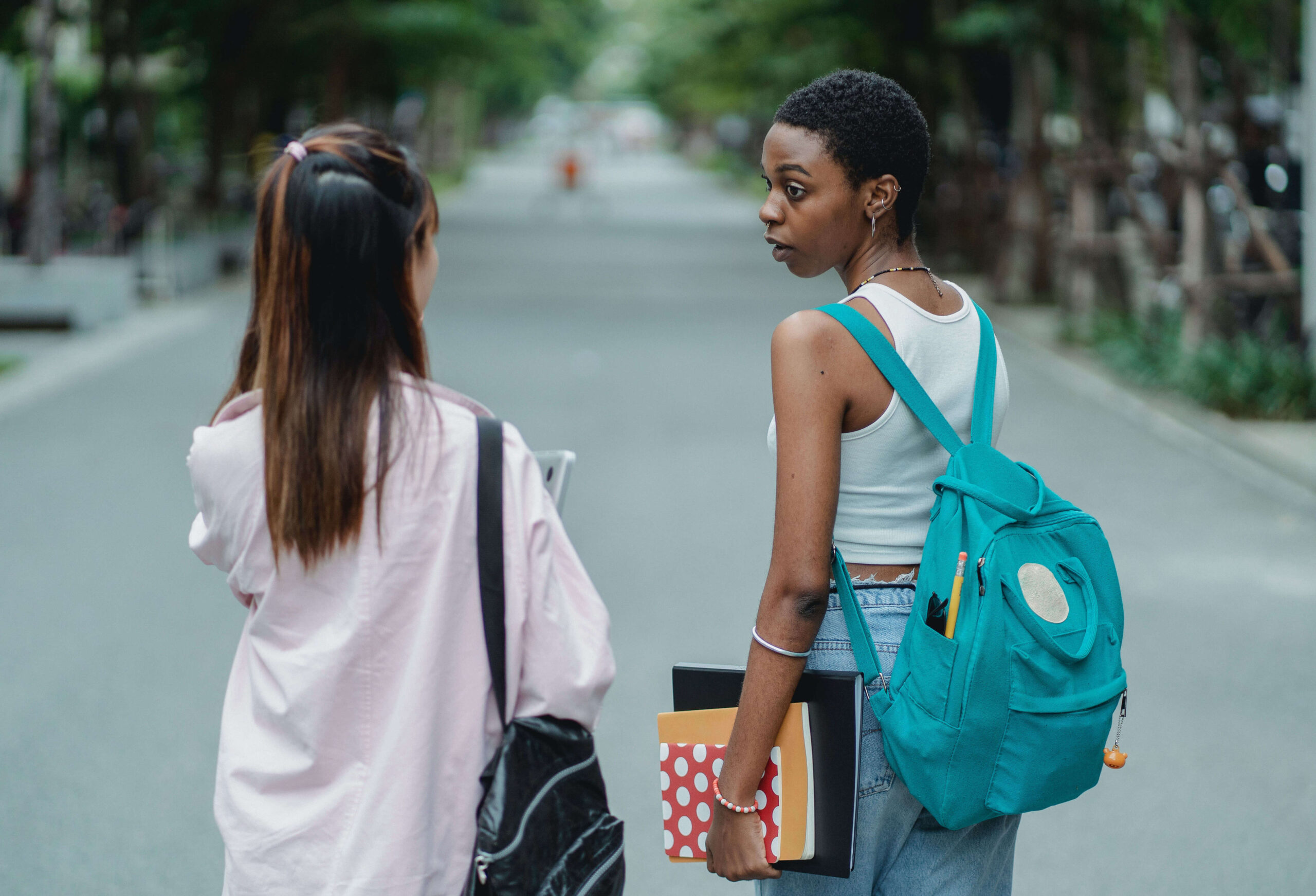 two students talking to one another while walking down the street