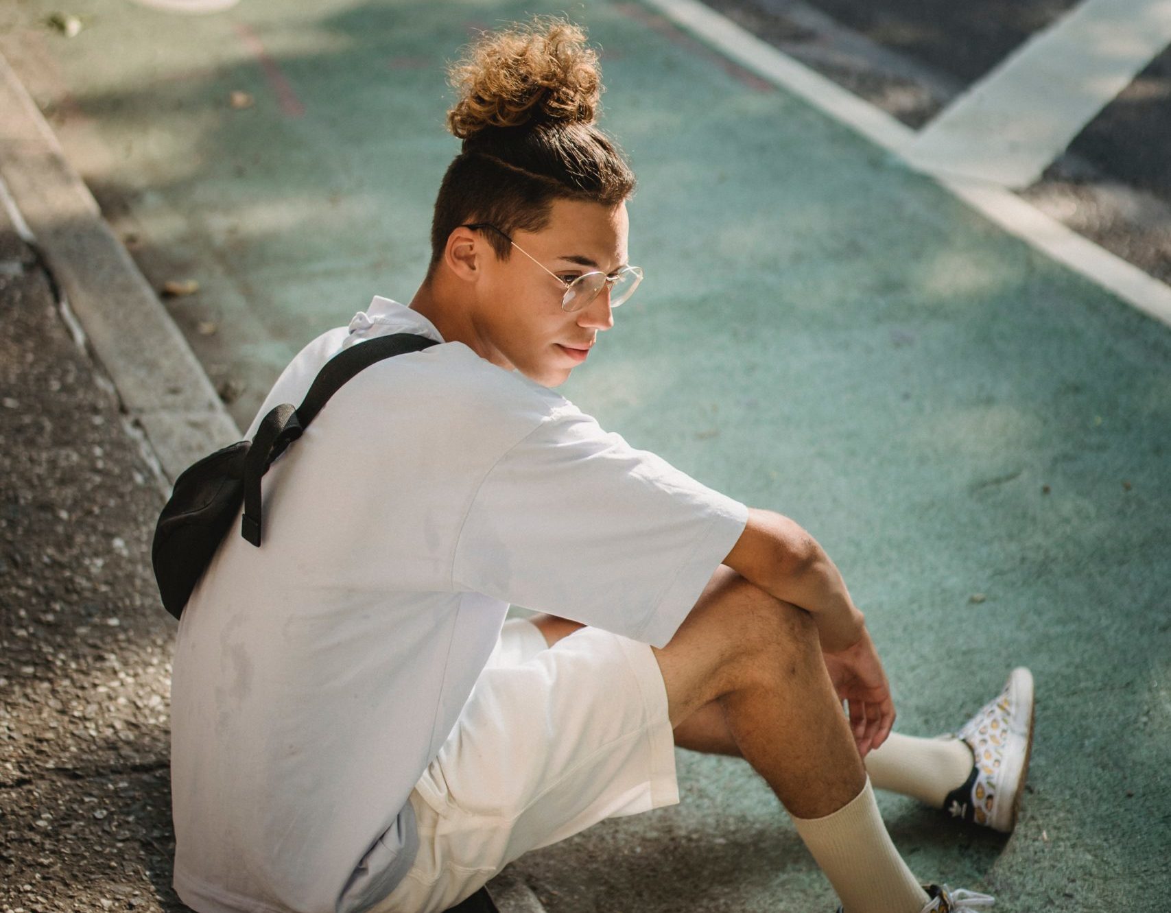 young man sitting on the sidewalk deep in thought