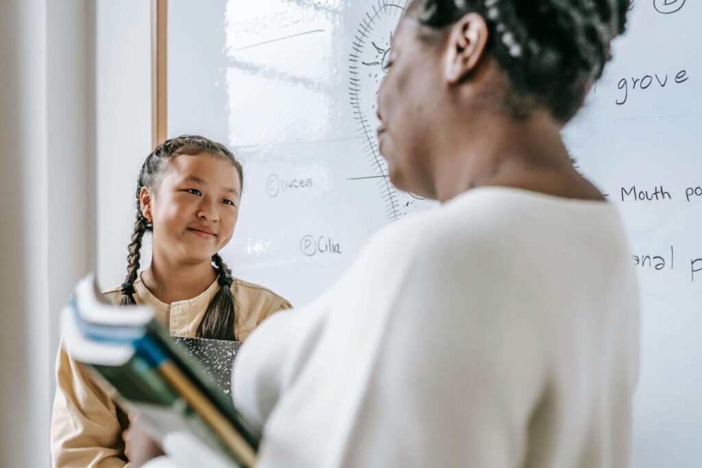 A young student looks up and smiles at their teacher.
